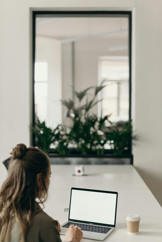 Woman working on a laptop in a modern home office with plants.