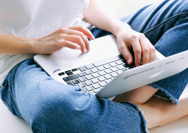 Woman sitting cross-legged in casual jeans working on a laptop indoors.